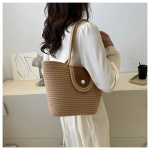 Détail du sac cabas en paille tressée avec rabat en cuir brun et bouton perle décoratif
