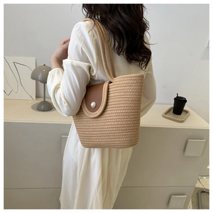 Détail du sac cabas en paille tissée avec rabat en cuir et élégant bouton perle