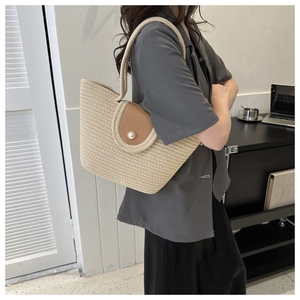 Détail d'un sac cabas tissé avec un rabat en cuir et un grand bouton perle décoratif