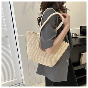 Mannequin portant un grand sac cabas tressé beige montrant le porté épaule décontracté