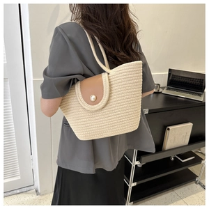 Détail d'un sac cabas en paille tressée avec rabat en cuir et bouton perle élégant