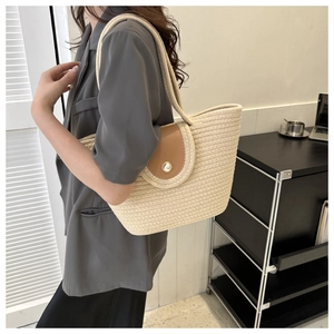 Détail d'un sac cabas tissé avec rabat en cuir et une grande perle décorative élégante