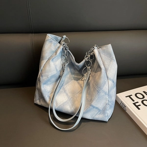 Light blue denim plaid tote bag with metal chain straps shown in a fashion setting