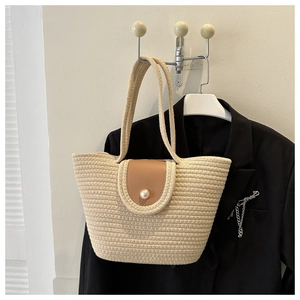 Détail du cabas tissé beige avec rabat en cuir et fermeture élégante en perle