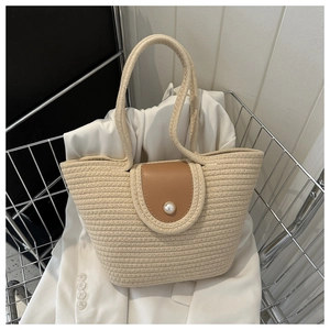 Détail d'un sac cabas en paille tressée avec rabat en cuir et fermoir perle