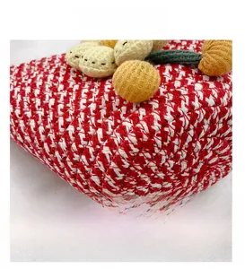Detail view of red and white hand-woven bucket bag with yellow knitted floral accents