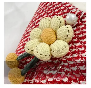 Detail of red tweed shoulder bag with a handmade knitted sunflower and faux pearl bead