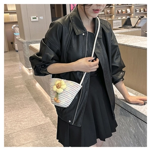 White woven bucket bag with yellow floral details worn by a model in a black leather jacket