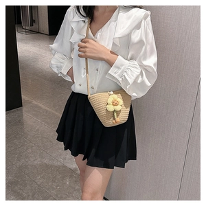Straw bucket bag with a yellow flower decoration and pearl closure on a female model