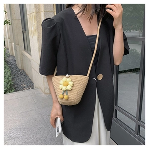 Detail of hand-woven straw bucket bag with yellow flower decor and pearl closure