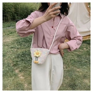 Detail of woven bucket bag with yellow flower charm during an outdoor picnic photoshoot
