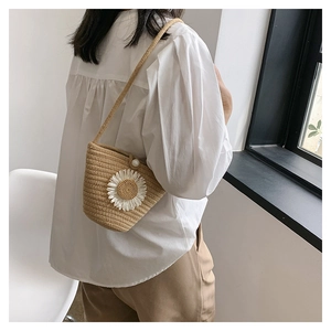 Détail du sac en paille tissé avec fleur de tournesol et bouton perle sur un mannequin