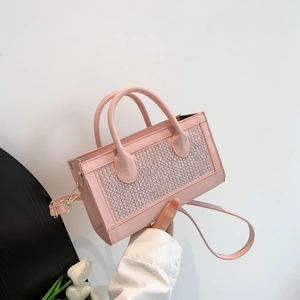 Sac à main rose avec strass, doubles poignées et bandoulière dorée sur fond blanc