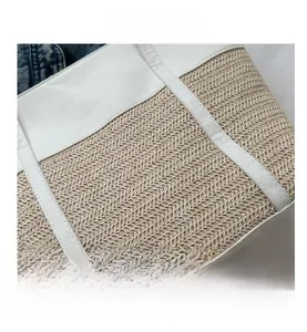 Close-up of woven tote bag showing white faux leather stitching and straw texture details