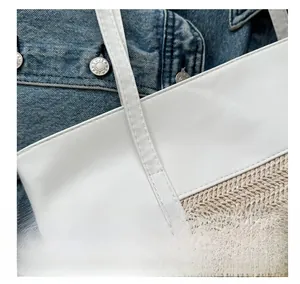 Detail shot of precise stitching on ivory leather and straw woven tote bag