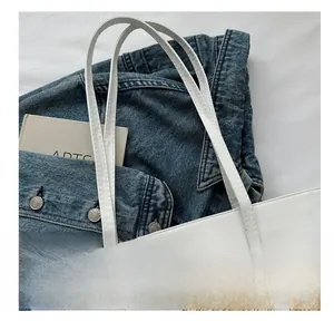 Close-up of woven texture and white leather handles on a large summer tote bag