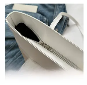 Detailed view of the smooth silver zipper closure on a white woven leather tote bag