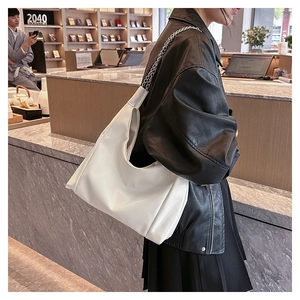 Détail du sac hobo en cuir blanc avec chaîne argentée porté par un mannequin en librairie
