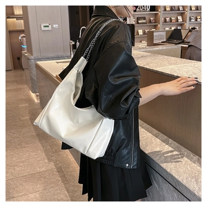 Détail d'un sac hobo blanc avec chaîne argentée et design minimaliste élégant
