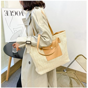Detail of a large woven tote bag featuring cream knit texture and brown leather accents