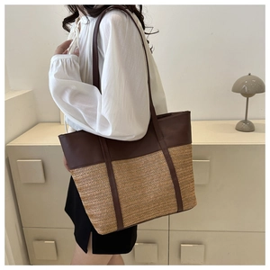 Detail of the woven straw texture and premium dark brown leather stitching on the tote bag