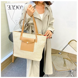 Detail view of woven straw tote bag with brown faux leather pocket and pearl button closure