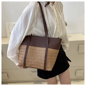 Close-up of large straw tote bag with brown leather contrast strap and textured weave