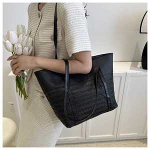 Close-up of black patchwork tote with premium straw weave texture and leather straps