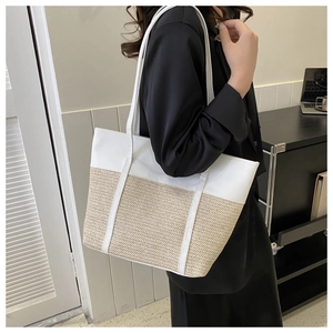 Detail of large straw patchwork tote bag featuring white PU leather and summer woven texture
