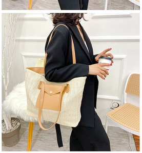 Close-up of a large woven straw tote bag with brown leather pocket and pearl button detail