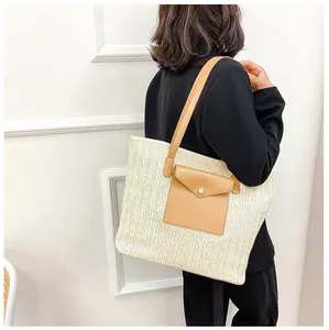 Detail of straw tote bag with brown leather pocket and elegant pearl buckle closure
