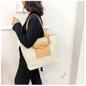 Detail of woven straw tote bag with brown leather pocket on human model in black suit