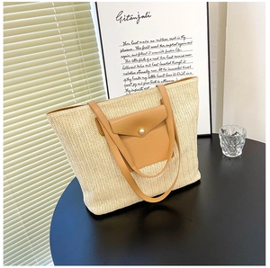 Detail of woven straw tote bag with brown leather pocket and pearl buckle decoration