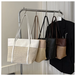 Detail of woven straw tote bags in four colors hanging on a minimalist metal rack