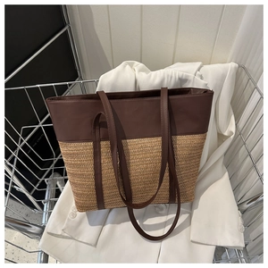 Detail view of the elegant mixed-material straw tote bag inside a metallic basket