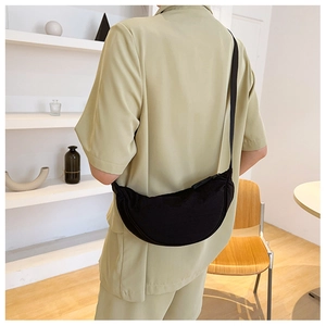 Close-up of minimalist black nylon crescent bag worn with casual outfit on shoulder