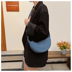 Blue nylon crescent bag worn by model in casual street style with a wide shoulder strap