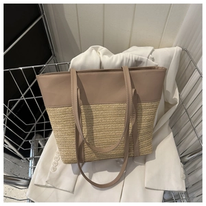 Detail of large straw tote bag with brown synthetic leather patchwork on white blazer