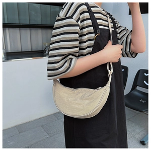 Detailed view of beige crescent moon crossbody bag with adjustable strap on model