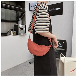 Detail of a terracota half-moon crossbody bag with wide adjustable shoulder strap