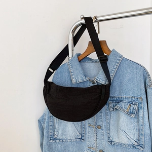 Detail of a minimalist black half-moon nylon crossbody bag with adjustable strap