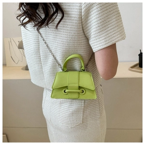 Détail du sac trapèze vert citron avec chaîne métallique et poignée sur tenue en tweed