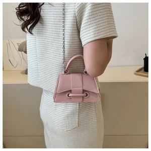 Detail of pink faux leather crossbody bag with silver chain strap on model