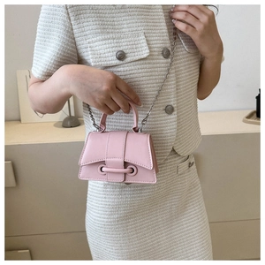Detail of pink hourglass leather crossbody bag with silver chain strap on light outfit
