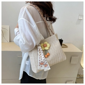 Detail of straw woven tote bag featuring floral pendant and decorative silk scarf