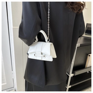 Detail of white glossy leather handbag featuring silver chain and curved hourglass base