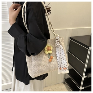 Detail of beige straw tote bag featuring a woven V-pattern and decorative yellow floral charm
