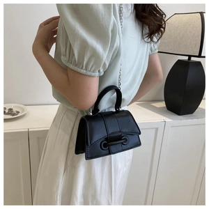 Side view of black leather crossbody bag with silver chain strap on model in modern setting