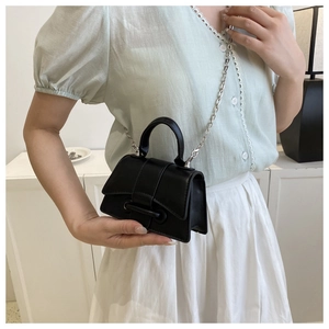Détail d'un mini sac à bandoulière en cuir noir avec chaîne argentée sur mannequin