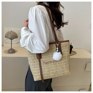 Detail of woven straw tote bag with brown leather straps and plush pearl charm